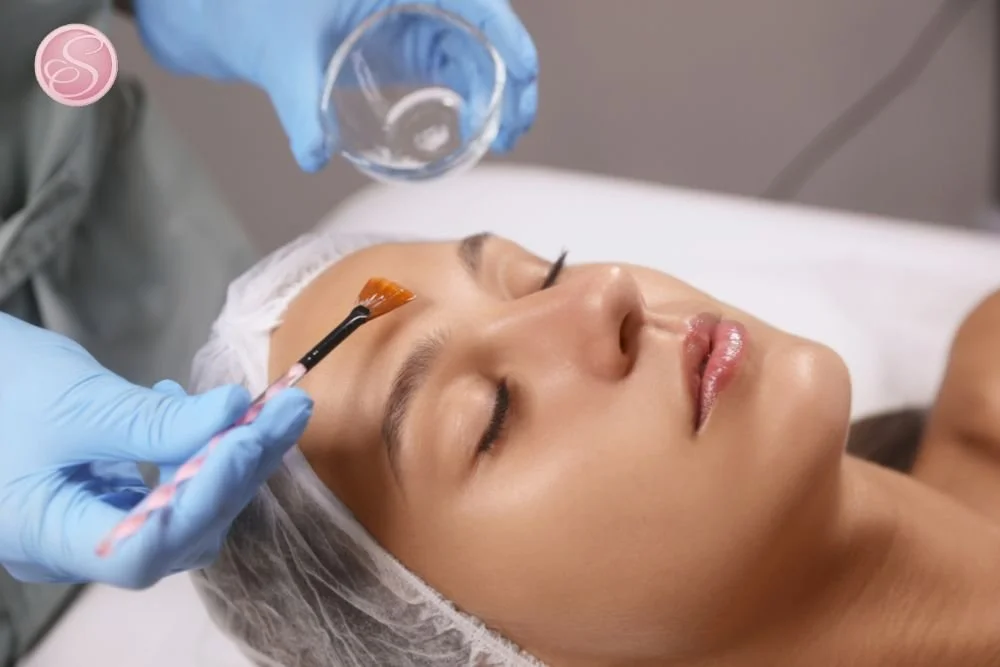 Esthetician evaluating skin texture closely before applying a professional exfoliating facial treatment