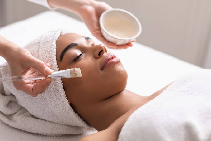 Esthetician evaluating skin texture closely before applying a professional exfoliating facial treatment